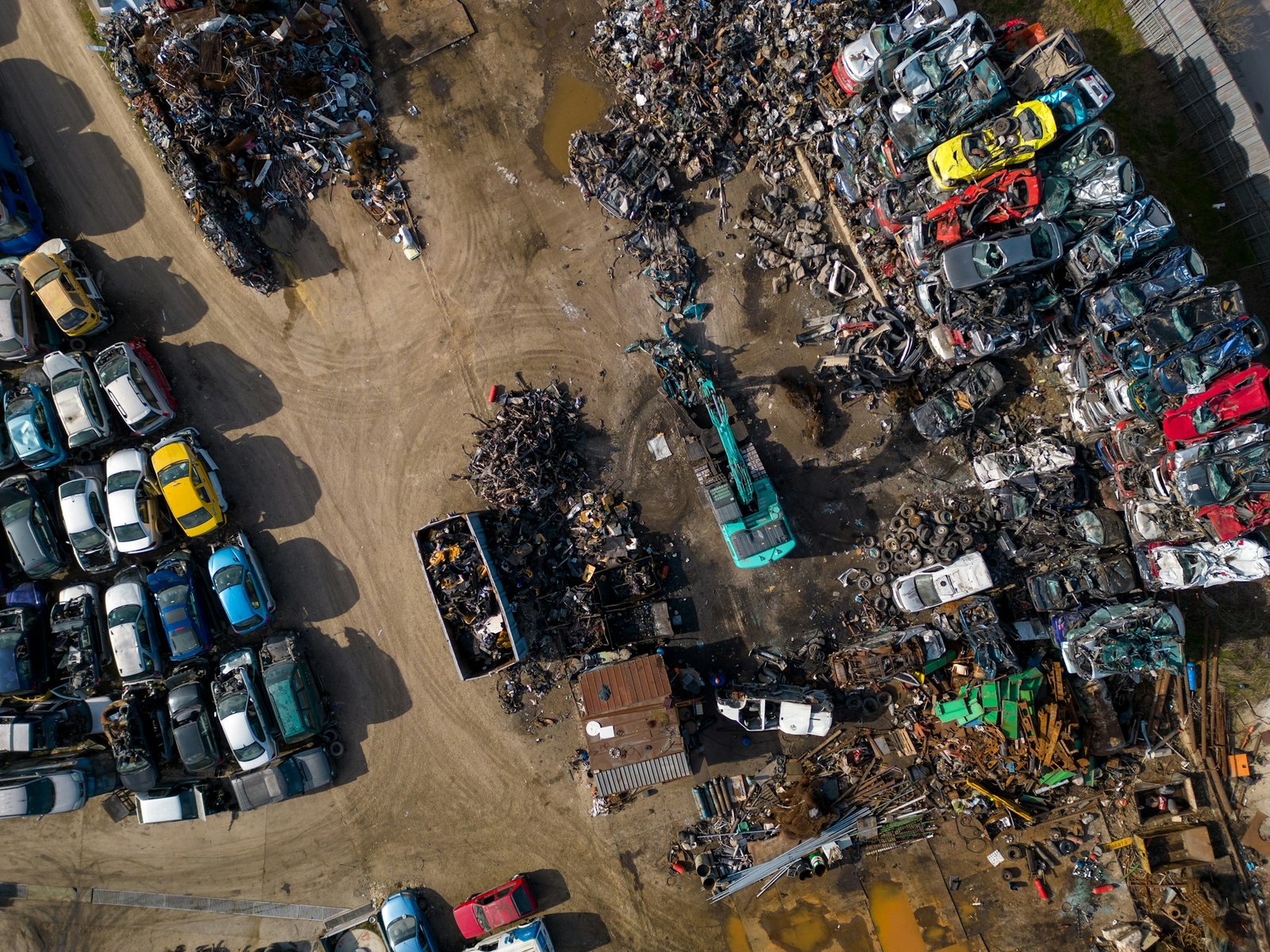 aerial view of a car dump, where a machine is seen separating old cars into scrap.