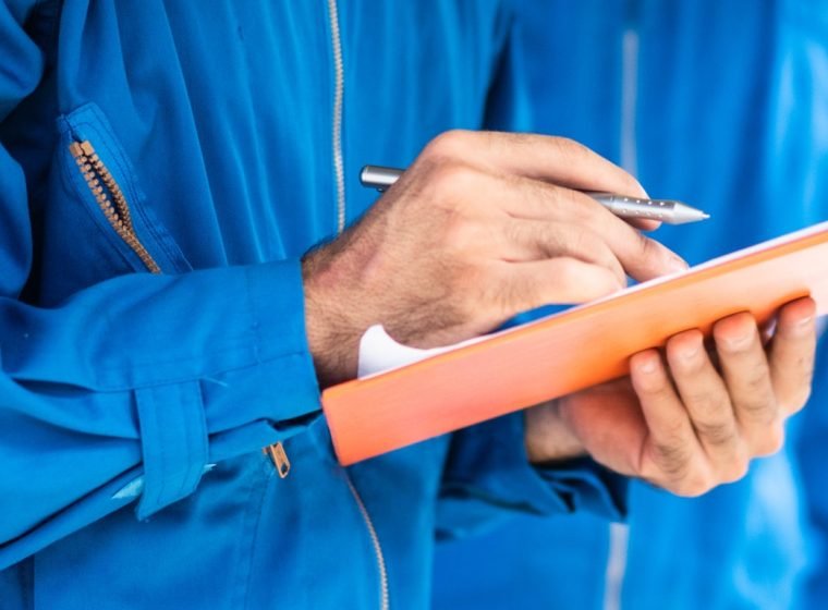 Automotive mechanic man checking car damage on checkilist document