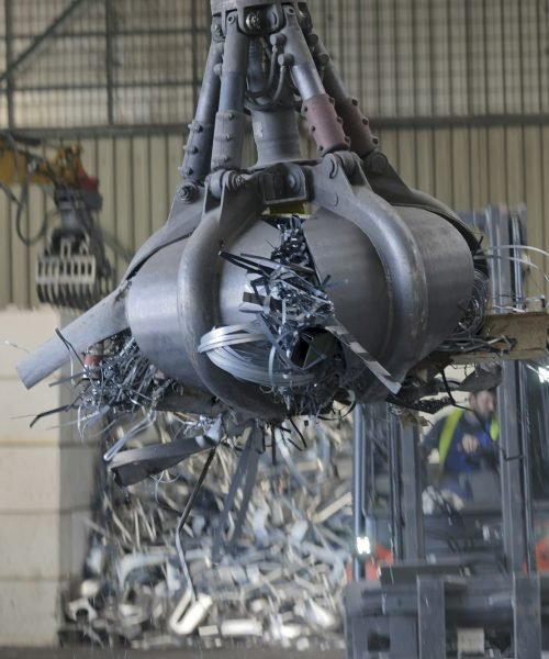 Clamshell grabbing scrap in a scrap metal recycling plant